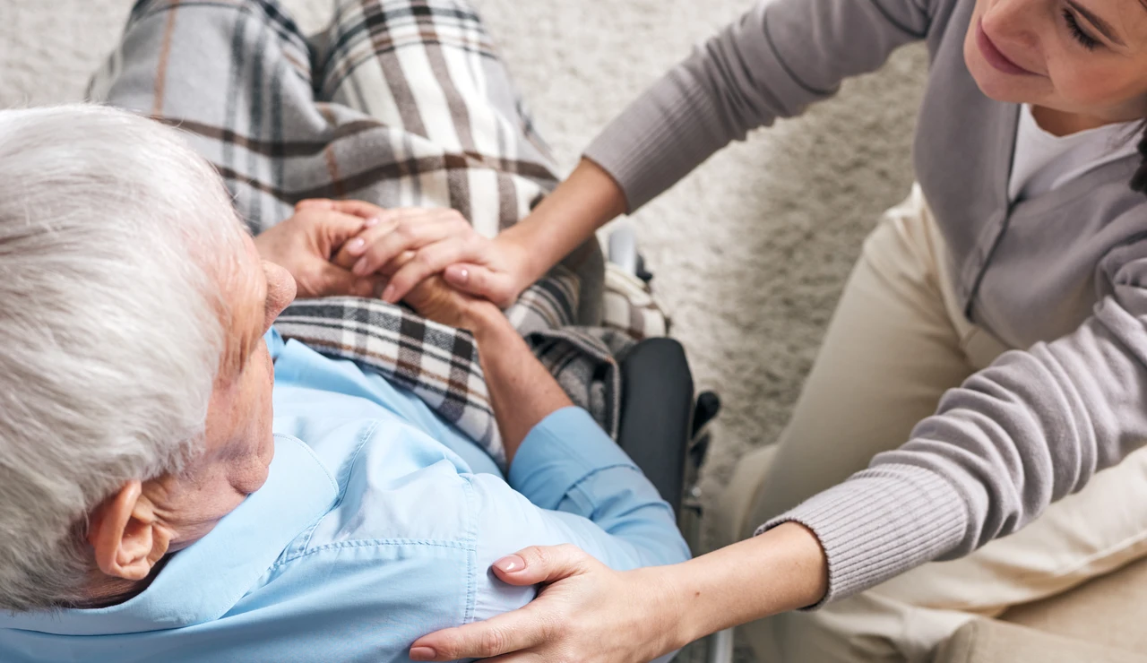 Una mujer cuida de un hombre en silla de ruedas