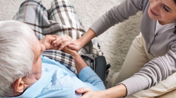 Una mujer cuida de un hombre en silla de ruedas