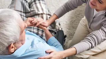 Una mujer cuida de un hombre en silla de ruedas Una mujer cuida de un hombre en silla de ruedas