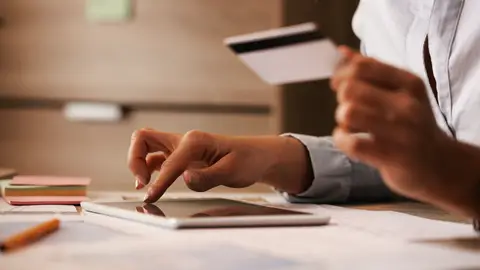 Una mujer con una tarjeta de crédito y una tablet Una mujer con una tarjeta de crédito y una tablet