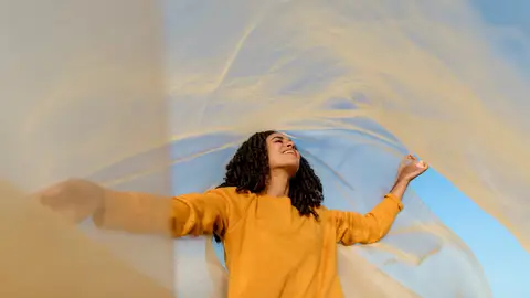 Una mujer sostiene una ligera tela Una mujer sostiene una ligera tela