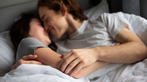 Pareja se abraza en la cama