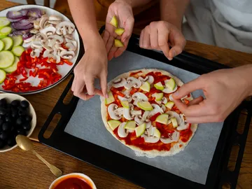 Dos personas cocinando una pizza Dos personas cocinando una pizza