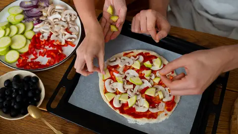 Dos personas cocinando una pizza Dos personas cocinando una pizza
