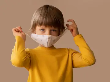 Un niño se pone una mascarilla Un niño se pone una mascarilla