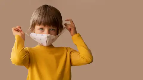 Un niño se pone una mascarilla Un niño se pone una mascarilla