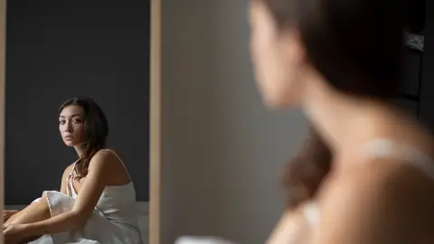 Mujer mirándose al espejo reflexiva Mujer mirándose al espejo reflexiva