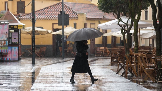 Imagen de archivo de una mujer caminando bajo la lluvia en La Laguna Imagen de archivo de una mujer caminando bajo la lluvia en La Laguna