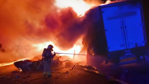 Un bombero apagando el fuego de un cami&oacute;n