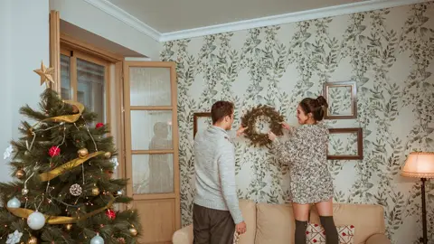 Pareja decorando su hogar con adornos navideños Pareja decorando su hogar con adornos navideños