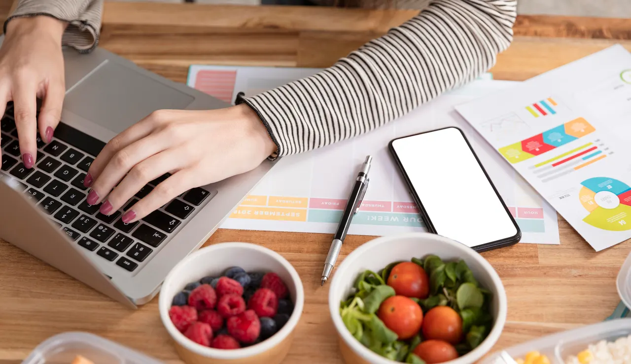 Una mujer con el ordenador rodeada de comida