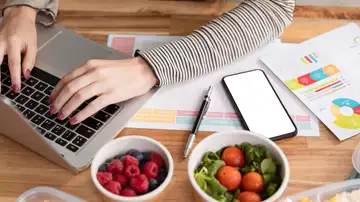 Una mujer con el ordenador rodeada de comida Una mujer con el ordenador rodeada de comida