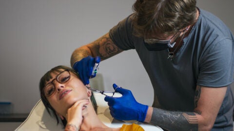 Una mujer se hace un piercing en la oreja en un centro de tatuajes
