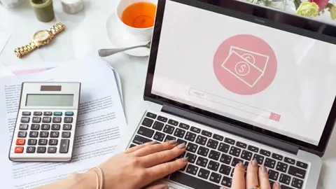 Una mujer con un ordenador y una calculadora Una mujer con un ordenador y una calculadora