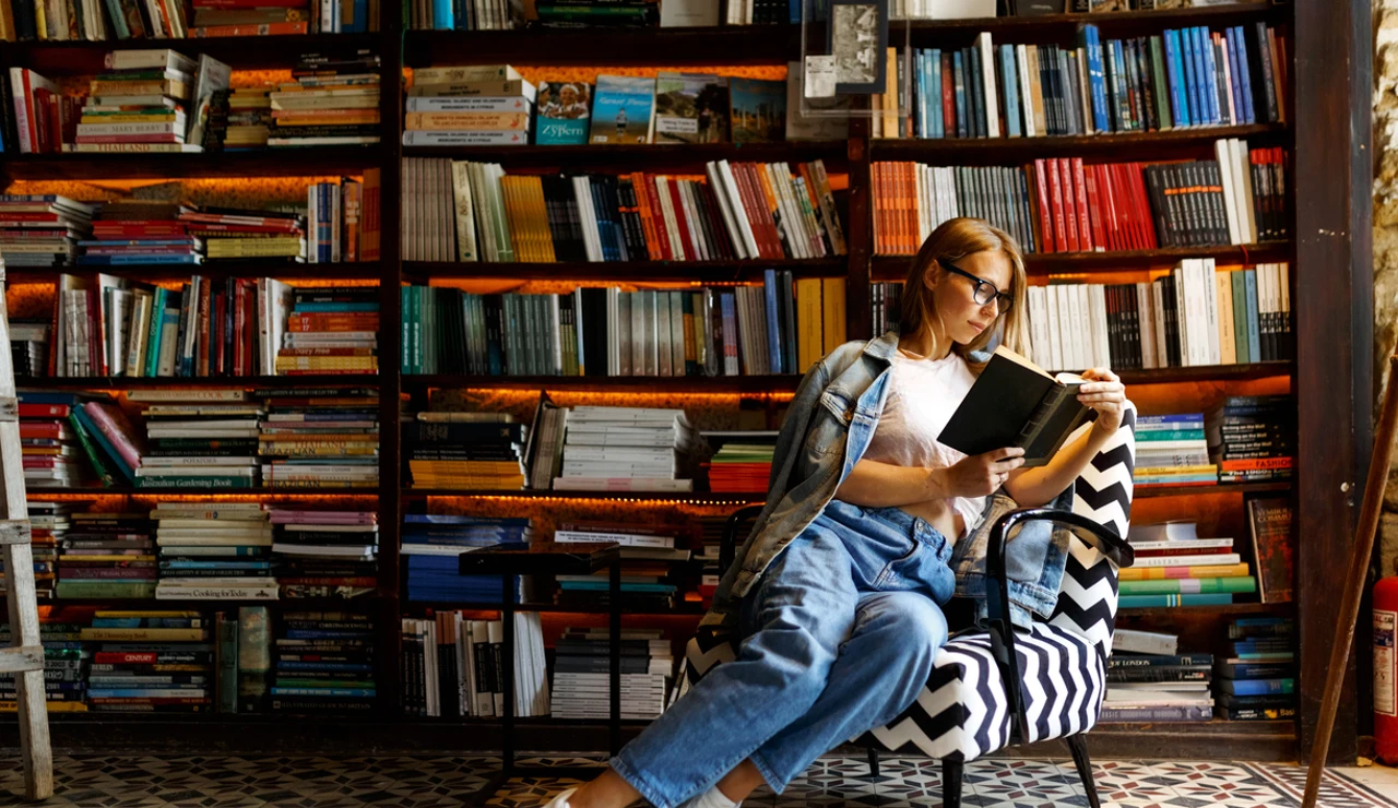 Mujer leyendo rodeada de estanterías de libros
