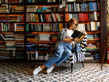Mujer leyendo rodeada de estanterías de libros Mujer leyendo rodeada de estanterías de libros