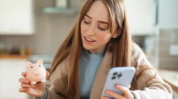 Una mujer joven con una hucha y un móvil Una mujer joven con una hucha y un móvil