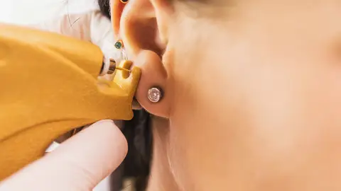 Una mujer se hace un piercing en la oreja Una mujer se hace un piercing en la oreja