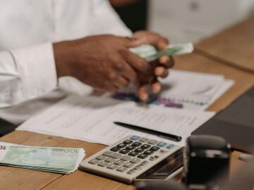 Imagen de una persona contando billetes con una calculadora 