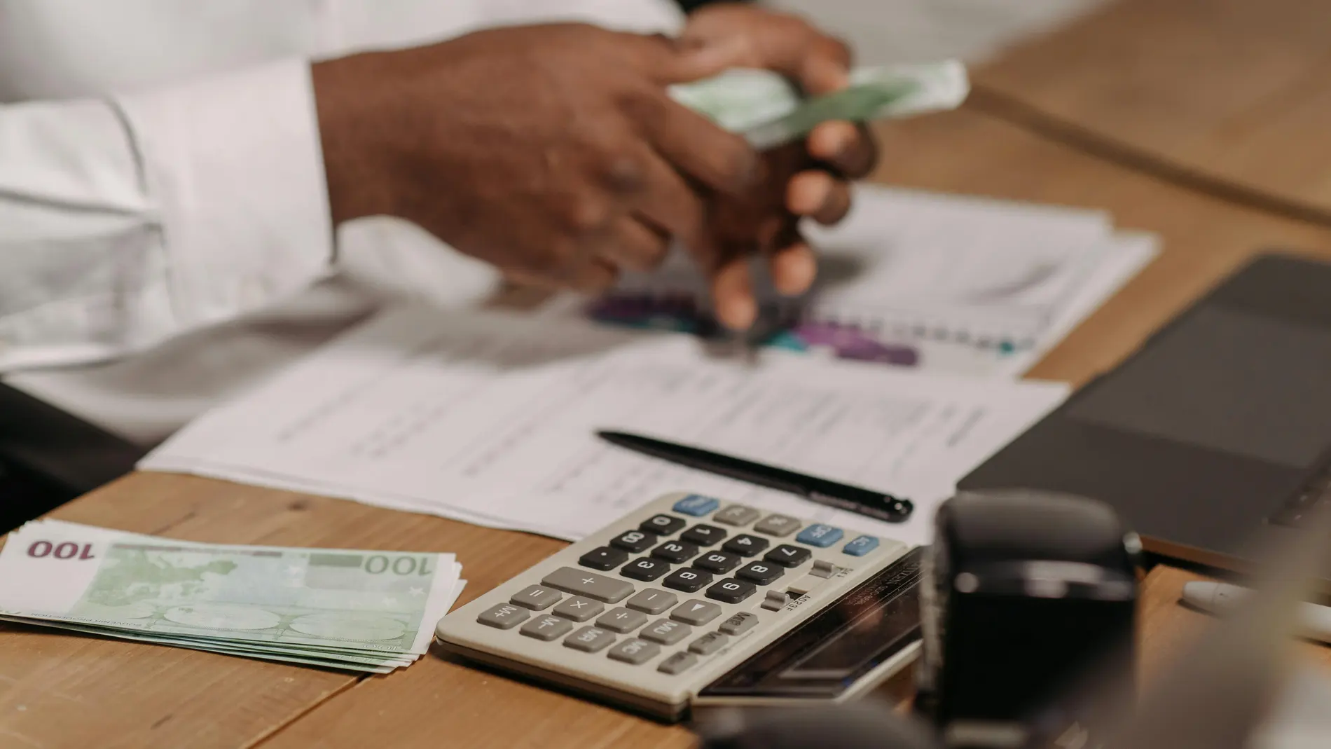 Imagen de una persona contando billetes con una calculadora Imagen de una persona contando billetes con una calculadora