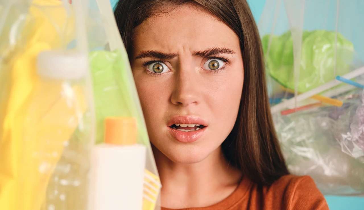 Mujer con cara de susto rodeada de productos de plástico