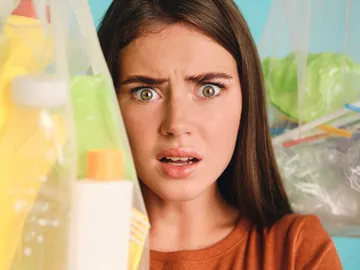 Mujer con cara de susto rodeada de productos de plástico Mujer con cara de susto rodeada de productos de plástico