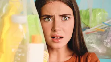 Mujer con cara de susto rodeada de productos de plástico Mujer con cara de susto rodeada de productos de plástico