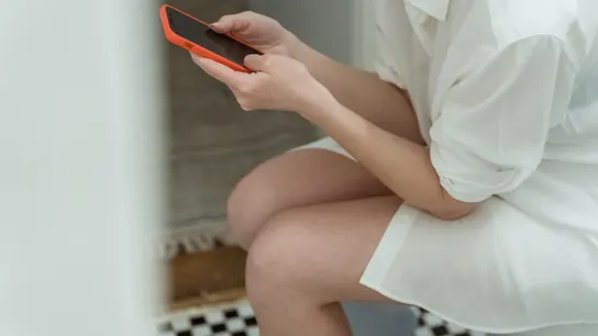 Imagen de una persona sentada en el váter con el móvil Imagen de una persona sentada en el váter con el móvil
