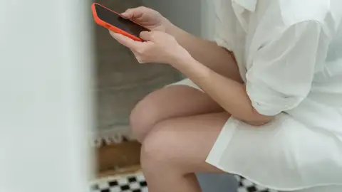 Imagen de una persona sentada en el váter con el móvil Imagen de una persona sentada en el váter con el móvil