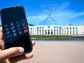 Un móvil muestra redes sociales en frente de la Casa Parlamentaria en Canberra, Australia
