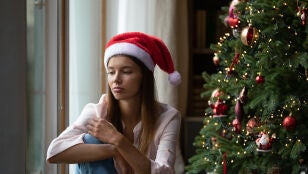 Una mujer pensativa junto al &aacute;rbol de Navidad