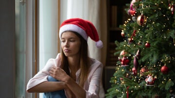 Una mujer pensativa junto al &aacute;rbol de Navidad