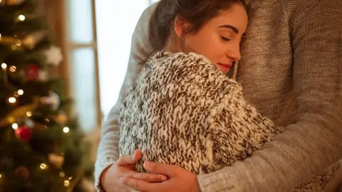 Mujer abraza aun hombre en Navidad Mujer abraza aun hombre en Navidad