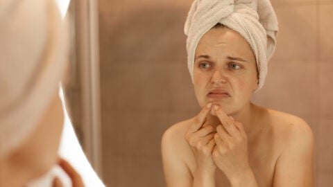 Una mujer con cara de disgusto frente al espejo