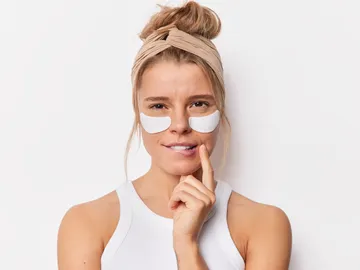 Una mujer joven con parches en el contorno de ojos Una mujer joven con parches en el contorno de ojos