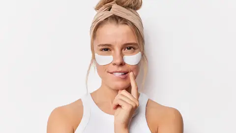 Una mujer joven con parches en el contorno de ojos Una mujer joven con parches en el contorno de ojos