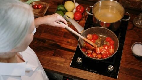 Mujer cocinando tomates cherri