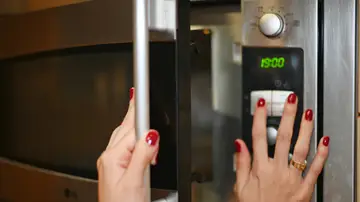 Chica abriendo el microondas Chica abriendo el microondas