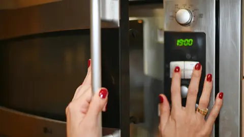 Chica abriendo el microondas Chica abriendo el microondas