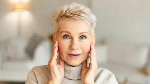 Mujer tensándose la cara Mujer tensándose la cara