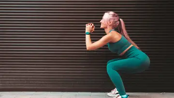 Una mujer joven haciendo una sentadilla Una mujer joven haciendo una sentadilla