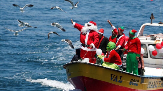 Un hombre vestido de Pap&aacute; Noel saluda a la gente desde un barco de pescadores en la v&iacute;spera de Navidad en la costa de Valpara&iacute;so, Chile