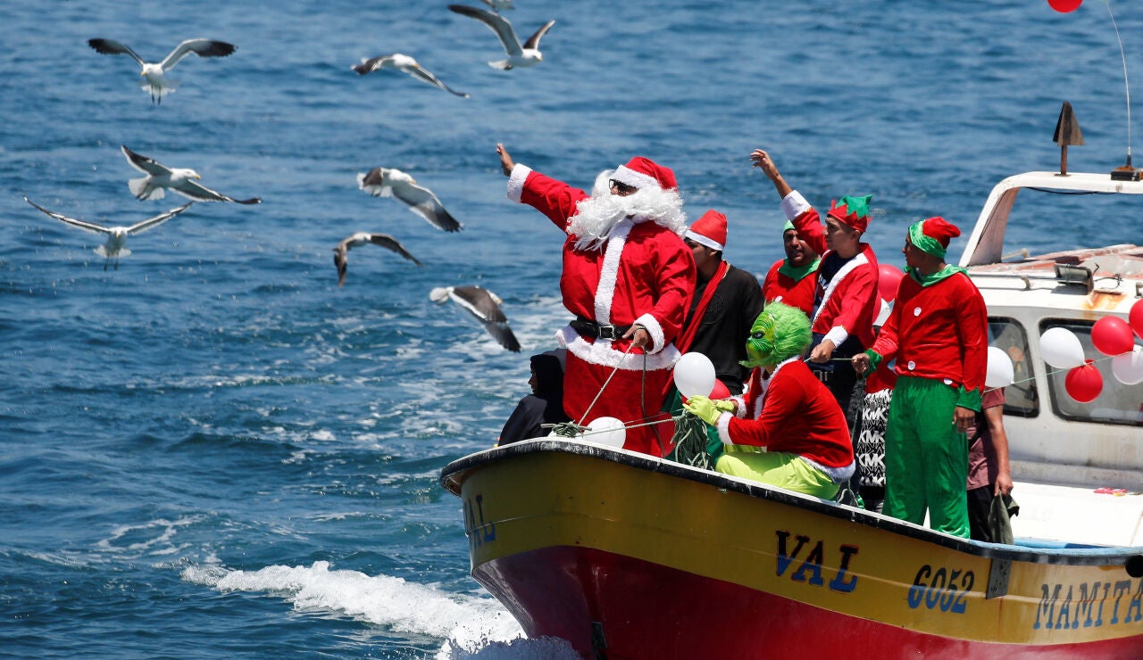 Un hombre vestido de Pap&aacute; Noel saluda a la gente desde un barco de pescadores en la v&iacute;spera de Navidad en la costa de Valpara&iacute;so, Chile
