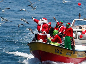 Un hombre vestido de Pap&aacute; Noel saluda a la gente desde un barco de pescadores en la v&iacute;spera de Navidad en la costa de Valpara&iacute;so, Chile