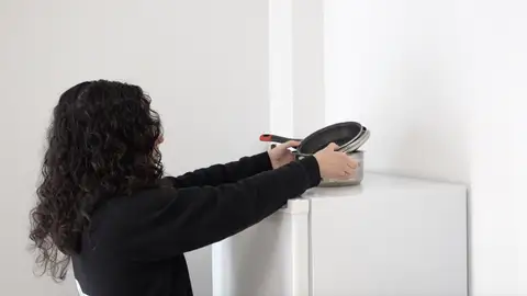 Persona colocando menaje encima de la nevera Persona colocando menaje encima de la nevera