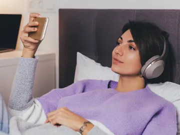 Mujer en la cama mirando una película con el teléfono Mujer en la cama mirando una película con el teléfono