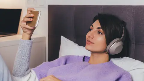 Mujer en la cama mirando una película con el teléfono Mujer en la cama mirando una película con el teléfono