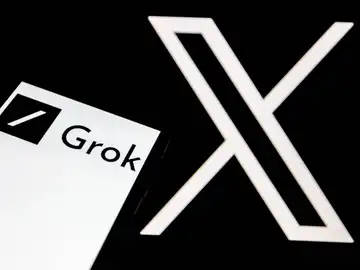 El logo de Grok aparece en la pantalla de un smartphone, y al fondo, el logo de la red social 'X' El logo de Grok aparece en la pantalla de un smartphone, y al fondo, el logo de la red social 'X'