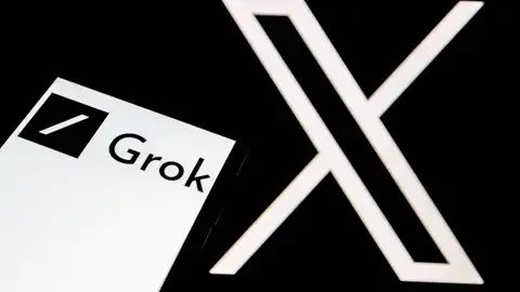 El logo de Grok aparece en la pantalla de un smartphone, y al fondo, el logo de la red social 'X' El logo de Grok aparece en la pantalla de un smartphone, y al fondo, el logo de la red social 'X'