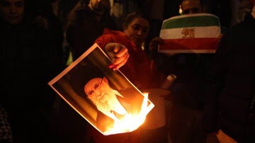 Un manifestante quemando la imagen del l&iacute;der iran&iacute; Ali Jamene&iacute;